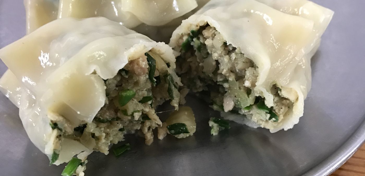 Steamed mandu with one torn open — pork, chives and tofu, which is the standard filling.