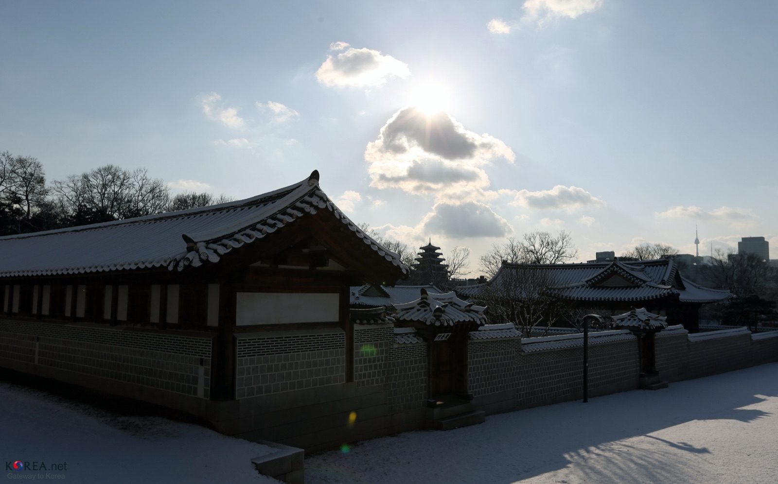 Snow covers the tiled roofs and courtyards of Gyeongbokgung Palace in Seoul under a bright winter sky