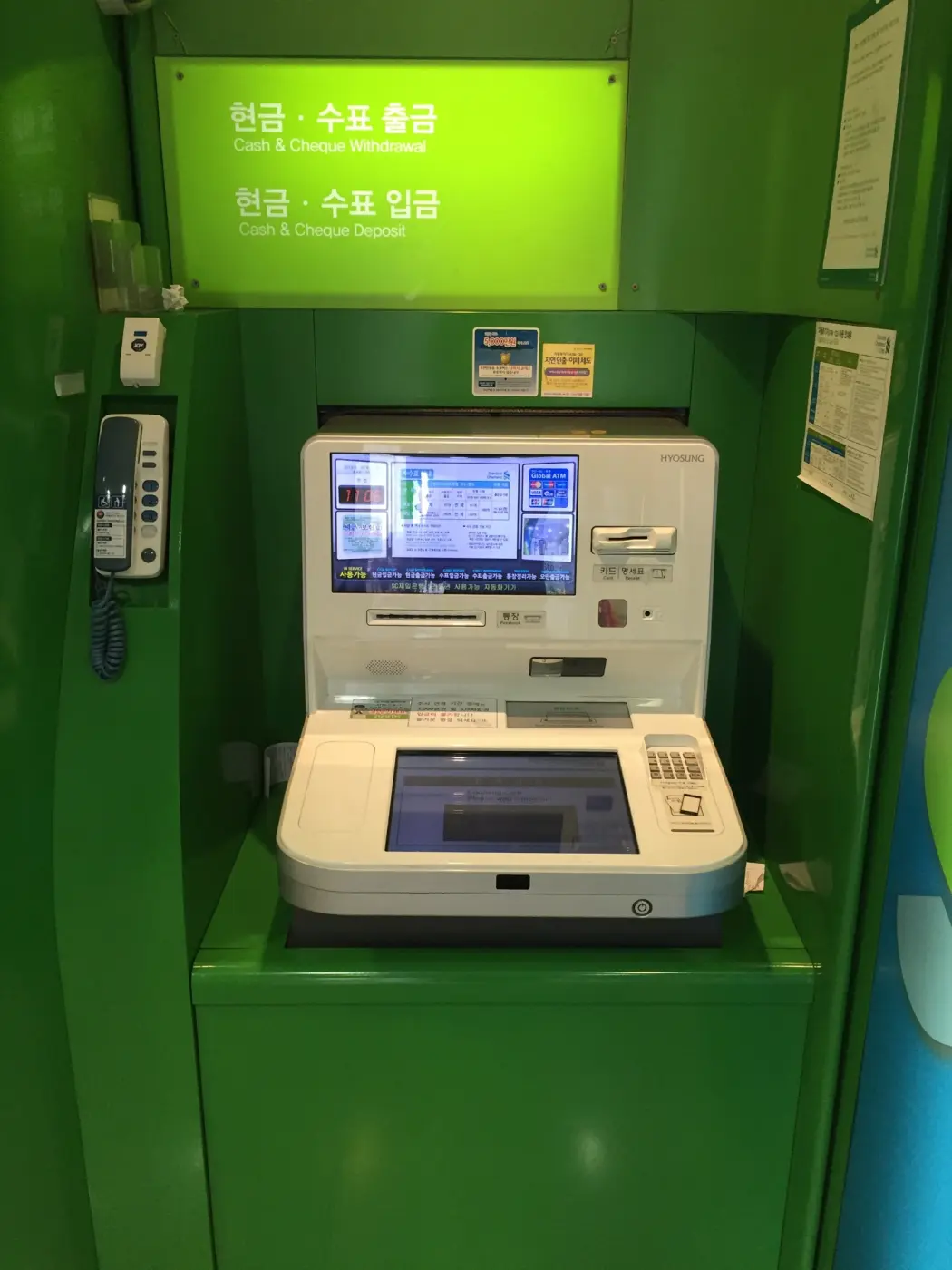 ソウルの銀行の緑色のブースに置かれたATM。画面に「Global ATM」の表示とカードブランドのロゴがある